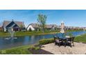 Outdoor patio with table and chairs overlooking a pond and manicured lawn at 15150 Mooring E Cir, Carmel, IN 46033