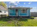 Lovely one-story light-blue home with a covered porch and lush green lawn at 1857 Calvin St, Indianapolis, IN 46203