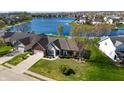 Aerial view of a well maintained brick home with a lake view and a green lawn at 1927 Westminster Pl, Columbus, IN 47201
