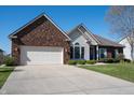 Charming brick and vinyl home featuring a well-manicured lawn and a two car garage at 1927 Westminster Pl, Columbus, IN 47201