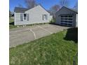 Features a cracked concrete driveway leading to a detached garage with a unique windowed garage door at 2018 Poplar St, Anderson, IN 46012