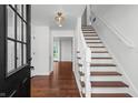 Elegant foyer with hardwood floors, a staircase with white risers, and a view into the home's bright interior at 3316 Eden Way Cir, Carmel, IN 46033