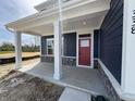 Inviting front porch with white columns, a red door, stone accents and navy blue siding at 338 Mcnair Dr, Whiteland, IN 46184