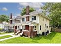 Delightful two-story home boasts brick details, a welcoming front porch, and a manicured lawn at 3544 Guilford Ave, Indianapolis, IN 46205