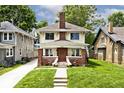 Inviting two-story home featuring brick accents, a cozy front porch, and landscaped lawn at 3544 Guilford Ave, Indianapolis, IN 46205