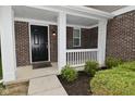 Charming front porch with brick accents, white columns, and neatly trimmed shrubs at 3930 Towhees Dr, Indianapolis, IN 46237