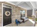 Inviting front porch with stone accents, seating area, and black front door with wreath at 4333 Ironclad Dr, Bargersville, IN 46106