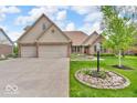 Charming brick home featuring a two-car garage, manicured lawn, and inviting curb appeal at 7113 Lakeside Woods Dr, Indianapolis, IN 46278