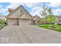 Two-story brick home with attached two-car garage and extended driveway and verdant landscaping at 7113 Lakeside Woods Dr, Indianapolis, IN 46278