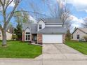 Attractive two-story home with brick facade, attached garage, manicured lawn and mature trees at 7775 Hollow Ridge Cir, Indianapolis, IN 46256