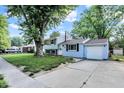 Light blue two-story home featuring an attached single garage, mature tree, and sunny skies at 7915 Broadview Dr, Indianapolis, IN 46227
