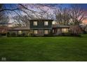 Beautifully lit home showcasing its stone accents and expansive green lawn at dusk at 13892 Adios Pass, Carmel, IN 46032