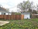 Large backyard featuring a wooden fence and storage shed, surrounded by green grass and blooming flowers at 212 W Burnside Ave, Fairland, IN 46126