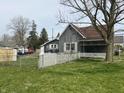 Rear view of the house with white fence in the yard and quaint architectural details at 214 S 10Th St, Elwood, IN 46036