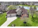 A beautiful brick house with a large lawn sits next to a pond at 2446 Quiet Way, Indianapolis, IN 46239