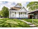 A charming two-story home with a covered porch and a well-manicured front lawn, surrounded by lush greenery at 3031 Nowland Ave, Indianapolis, IN 46201