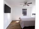 Inviting bedroom with a ceiling fan, a large window with blinds, a wall-mounted TV, and hardwood floors at 4421 Greenmeadow Ct, Indianapolis, IN 46235