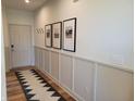 Inviting hallway showcasing wainscoting detail, elegant art, and a patterned runner on hardwood floors at 4810 Oak Hl Dr, Lebanon, IN 46052