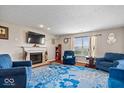 Cozy living room featuring a fireplace, hardwood floors, and comfortable blue furniture at 4922 Birmingham Dr, Indianapolis, IN 46235
