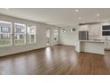 Open-concept living room with hardwood floors, bright windows, and a modern kitchen in the background at 5309 Spyglass Dr, Whitestown, IN 46075
