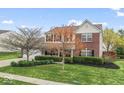 Inviting two-story brick home with green lawn, neat landscaping, and a two-car garage at 5817 Thompson Park Blvd, Indianapolis, IN 46237