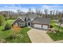Aerial view of a brick home with an attached three car garage and a large concrete driveway at 621 Foxboro Dr, Avon, IN 46123