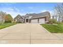 Charming brick home featuring an attached three car garage and a long concrete driveway at 621 Foxboro Dr, Avon, IN 46123
