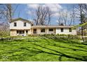 Inviting home exterior featuring stone accents, a spacious yard, and meticulous landscaping at 6454 Dean Rd, Indianapolis, IN 46220