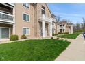 View of the building's exterior, showing balconies and manicured lawn at 6516 Emerald Hill Ct # 310, Indianapolis, IN 46237