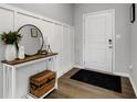 Stylish entryway featuring wainscoting, a round mirror above a wood and white console table, and hardwood floors at 6622 Cardiff Cir, McCordsville, IN 46055