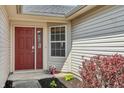 A cozy front porch with a red door and vibrant landscaping enhances curb appeal at 7048 Tassel Meadow Dr, Indianapolis, IN 46217