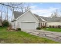 View of the home's side, showing the two-car attached garage, lush lawn, and well-kept landscaping at 7640 Bay Shore Dr, Indianapolis, IN 46240