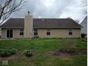 Rear exterior of home showcasing the siding, chimney, well maintained yard and mature trees at 8106 Captain Dr, Avon, IN 46123