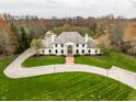 Majestic home showcases a pristine lawn, circular driveway, and elegant facade, surrounded by lush greenery at 8155 Hunt Club Rd, Zionsville, IN 46077