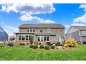 Backyard featuring a patio with comfortable seating, lush landscaping, and the home's neutral-colored exterior at 10235 Normandy Way, Fishers, IN 46040