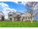 Charming two-story home with manicured lawn, showcasing neutral siding, brick accents, and a welcoming teal front door at 10235 Normandy Way, Fishers, IN 46040