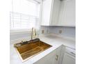 Close up of a stylish kitchen with a gold sink, quartz countertops, and white cabinets at 12516 Schoolhouse Rd, Fishers, IN 46037