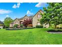 Beautifully landscaped stone home featuring a vibrant flower bed and mature trees at 13758 Foxdale Lake Dr, Carmel, IN 46032