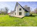 Spacious backyard with lush green grass, a cozy patio, a swing set, and charming white brick accents at 138 Fairway Dr, Indianapolis, IN 46260