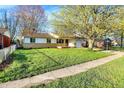 Well-kept single-story home showcases a lush green lawn, mature trees, and a welcoming facade at 1457 Biloxi Ln, Beech Grove, IN 46107