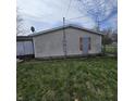 Exterior view of the home showing vinyl siding and boarded up window at 1704 E Kirk St, Muncie, IN 47303