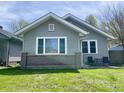 Charming single-story home with gray siding, white trim, and a brick accent with a seating area on the front patio at 1749 E 52Nd St, Indianapolis, IN 46205