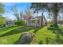 Quaint home with mature trees and a spacious front yard, showcasing its serene setting at 1917 W 58Th St, Indianapolis, IN 46228