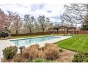 Backyard pool with a stone deck, pergola covered lounge area, brick privacy fence, and mature trees at 290 Breakwater Dr, Fishers, IN 46037