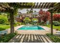 Backyard pool surrounded by lush garden and pergola with a view of the home at 290 Breakwater Dr, Fishers, IN 46037