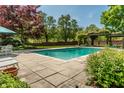 Backyard pool area with stone patio, mature trees, and privacy wall at 290 Breakwater Dr, Fishers, IN 46037