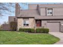 Charming townhome exterior with stone accents, well-manicured landscaping, and a red front door at 622 Conner Creek Dr, Fishers, IN 46038
