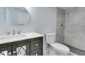 Bathroom with a gray vanity, updated fixtures, a round mirror, and tiled shower at 1125 N Colorado Ave, Indianapolis, IN 46201