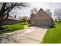 Wide driveway leading to an attached garage, complemented by a well-kept lawn and surrounding greenery at 11525 Capistrano Cir, Indianapolis, IN 46236