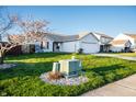 View of front yard featuring mature tree, green grass, and utility box with rock surround at 1696 Carlton Dr, Greenfield, IN 46140